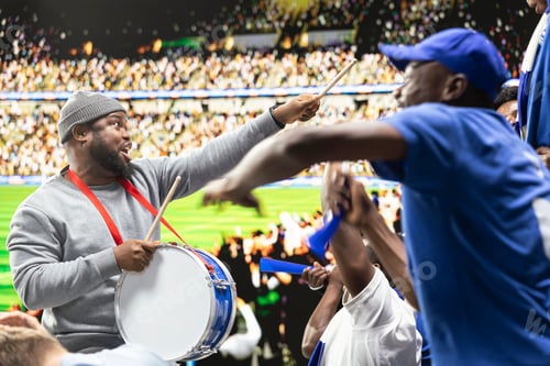 Preview: Dedicated football fan leader directing blue supporters with drum