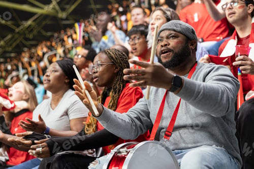 Preview: Black football supporter with drum gesturing anxiously with open hands