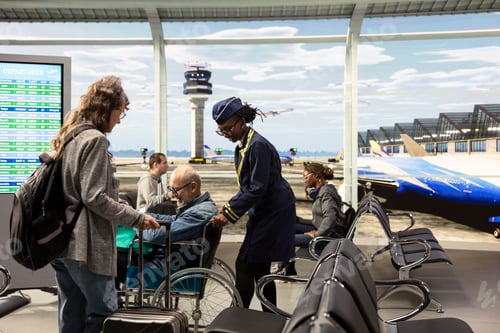 Preview: Professional flight attendant assisting elderly woman by pushing wheelchair user