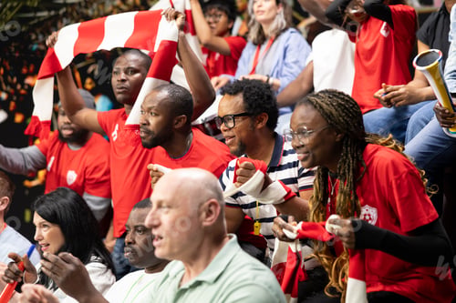 Preview: Female soccer fans celebrating goal with raised arms in crowded stadium stands