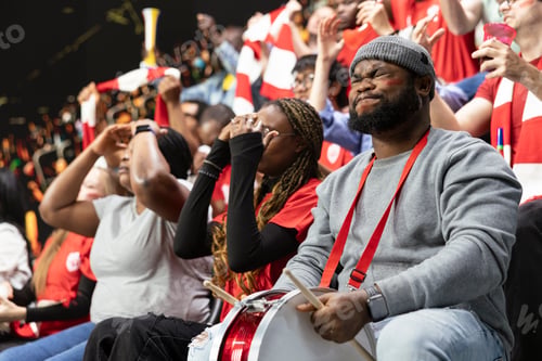 Preview: Black football supporter with drum closing eyes and holding breath