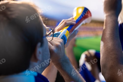 Preview: Close up of soccer fans singing with vuvuzelas in stadium tribunes
