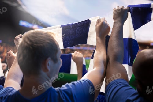 Preview: Close up of football supporters lifting scarf above head in stadium seats