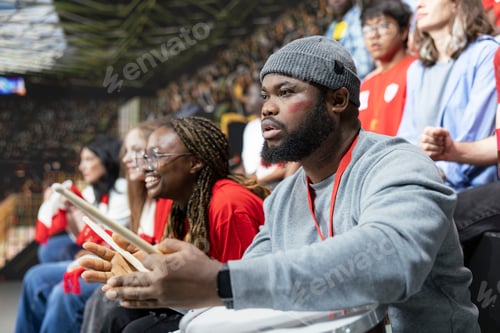 Preview: Focused Black football supporter with drum watching tense live soccer match