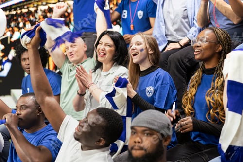 Preview: Blue team football supporters clapping and raising arms in stadium stands