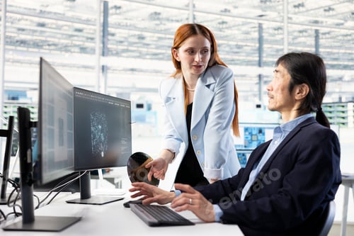 Preview: Female technician and coworker use AI to examine microchip circuit design