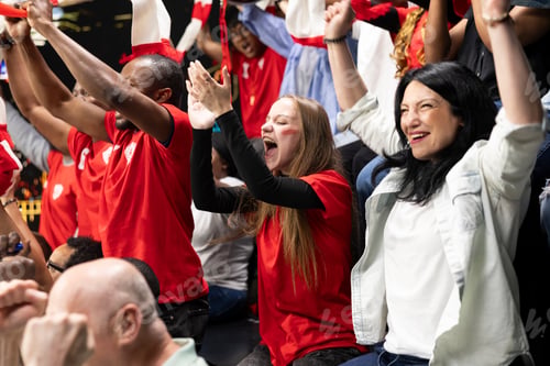 Preview: Female soccer fans celebrating goal with raised arms in crowded stadium stands