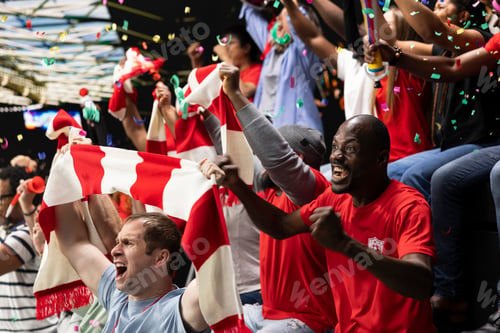Preview: Excited football supporters celebrating with confetti in stadium stands
