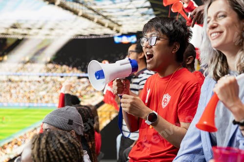 Preview: Energetic football fan leading chanting fans with loudspeaker in the stands