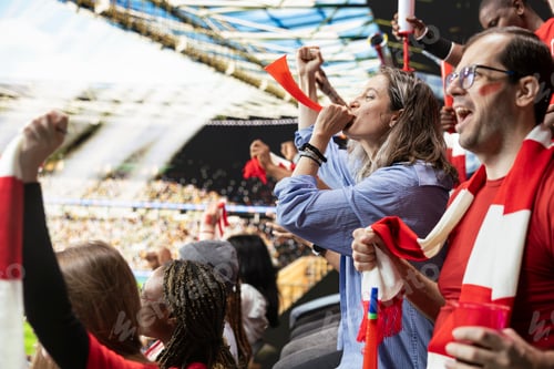 Preview: Woman football supporter blowing red horn from stadium stands