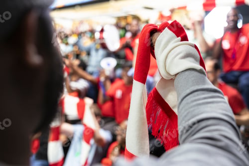 Preview: Close-up of supporter raising a red and white scarf during live soccer match