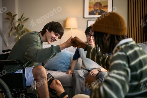 Preview: Teenage Boy with Disability Fist Bumping Friends at Home