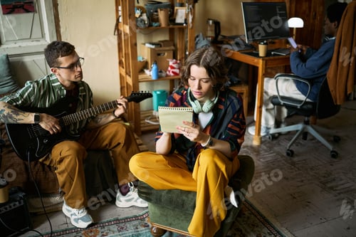 Preview: Adult Woman Writing Lyrics While Man Playing Guitar in Home Studio