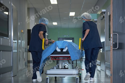 Preview: Adult Hospital Staff Transporting Patient on Gurney to Surgery