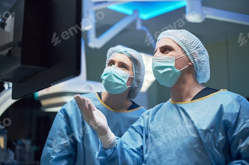 Preview: Adult Surgeons Reviewing Monitor during Operation Planning