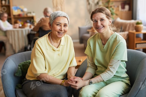 Preview: Portrait of Senior Woman and Female Caregiver Sitting in Nursing Home