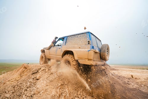 Preview: Off-road vehicle driving through muddy terrain stirring up earth