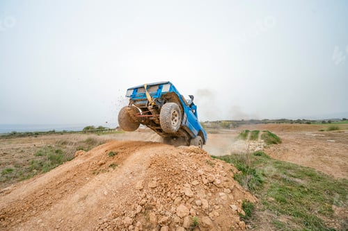 Preview: Blue off road vehicle jumping dirt mound during extreme driving
