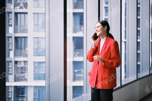 Preview: Hispanic businesswoman talking on mobile phone in modern high-rise workplace.