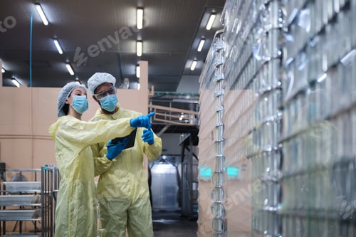 Preview: Two supervisors inspect quality of containers in canned food manufacturing.