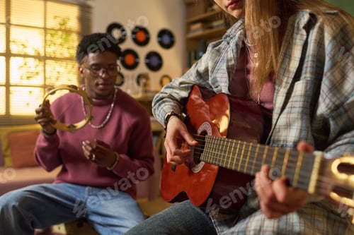 Preview: Teenage Girl Playing Guitar While Black Man Shaking Tambourine
