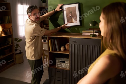 Preview: Man Hanging Framed Art during Home Styling
