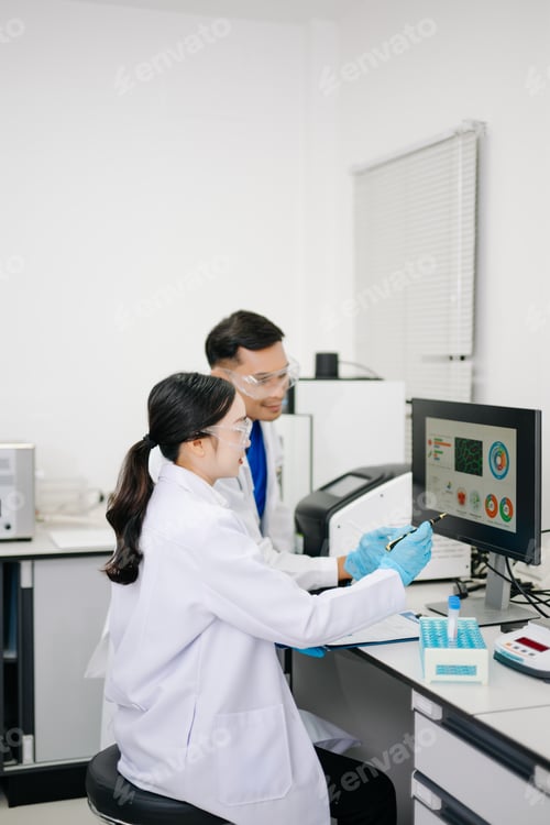 Preview: Two Asian Scientists Analyzing Data on Computer Monitor in Modern Laboratory