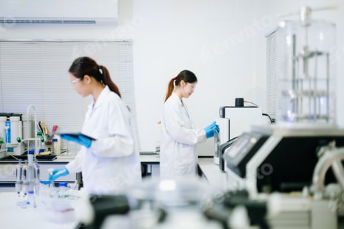 Preview: Two scientists working together in advanced laboratory using microscope and pipette for biotechnolog