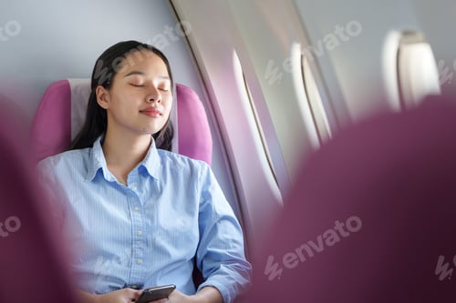 Preview: Asian woman relaxing with eyes closed on airplane during flight