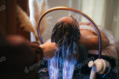 Preview: Close up of professional hands applying water and massaging scalp in spa