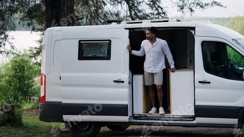 Preview: Man standing in modern camper van enjoying van life trip