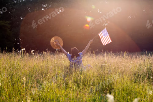 Preview: Woman with USA flag in green meadow.
