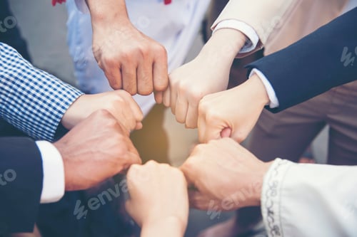 Preview: Group of diversity people with success partnership fist bump of hands together to show power and uni