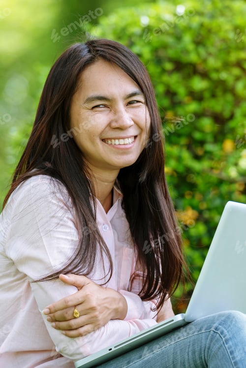 Preview: Vertical Horizon Asian woman sitting green park using laptop computer. Beautiful Woman working on la