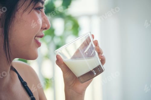 Preview: Women hands holding white glass of milk pouring from bottle. Asian women smile laugh look at camera