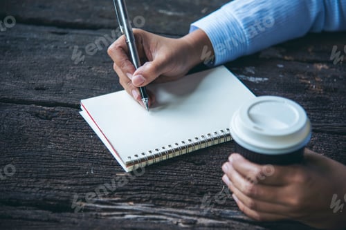 Preview: Woman hands writing empty notebook planing meeting agenda on wooden table. Close up women hands usin