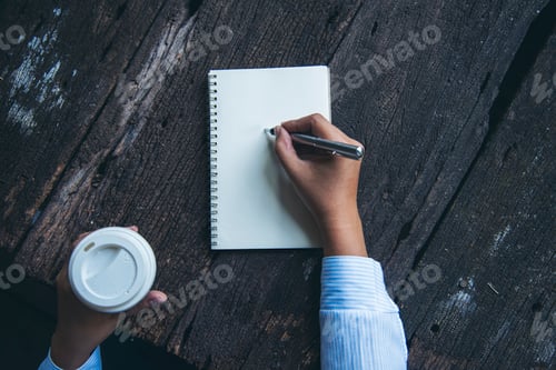 Preview: Woman hands writing empty notebook planing meeting agenda on wooden table. Close up women hands usin