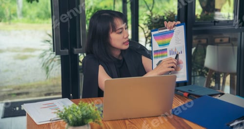 Preview: Business woman using smartphone, laptop on office desk. Female freelance reading financial graph cha