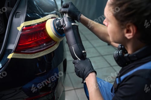Preview: Skilled auto detailer is polishing car taillight with orbital buffer