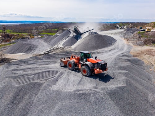 Preview: Granite quarry operation showing heavy machinery working on gravel piles and processing stone in a