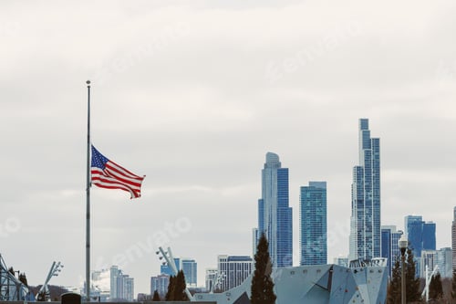 Preview: City skyline with American flag waving during cloudy weather in Chicago