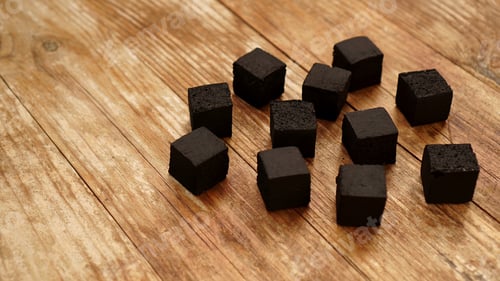 Preview: Cubes of coconut coal for hookah on wooden background.