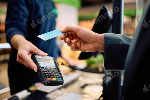 Preview: Close up of woman using credit card while paying in supermarket.
