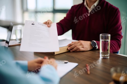 Preview: Close up of job candidate giving his CV to HR manager in the office.