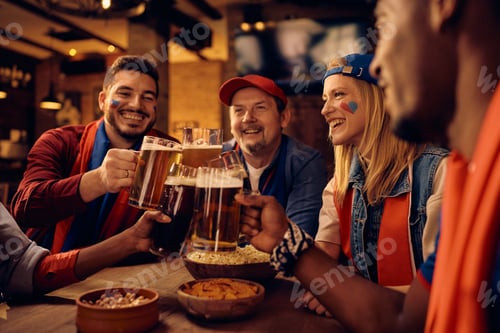 Preview: Happy woman and her friends toasting with beer during sports championship in a bar.