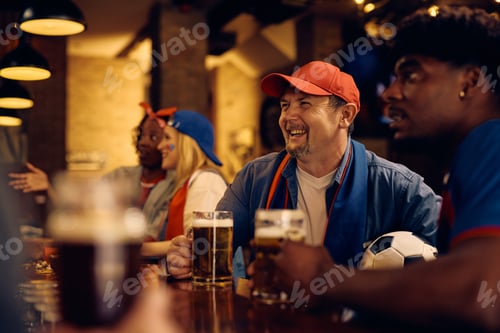 Preview: Happy sports fan watching football championship game in a pub.
