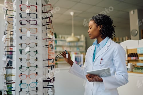 Preview: Africa American female optometrist working in optical shop.