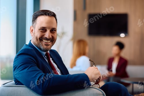 Preview: Happy businessman in the office looking at camera.