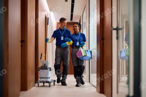 Preview: Cleaning staff members talking while working through office hallway.