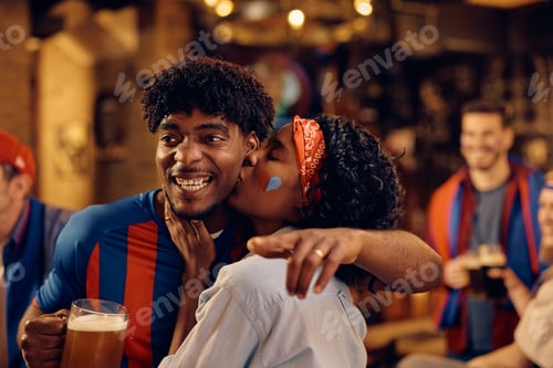 Preview: Happy black couple celebrating victory or their favorite team during sports championship.